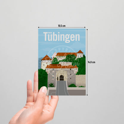 A hand holding a postcard of the Tübingen Castle on a white background.